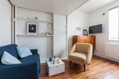 Cette photo montre une petite salle de séjour tendance fermée avec un mur blanc, parquet foncé, aucune cheminée et un téléviseur fixé au mur.