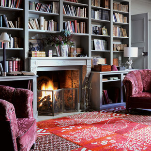 Inspiration pour une salle de séjour avec une bibliothèque ou un coin lecture traditionnelle fermée et de taille moyenne avec un mur gris, un sol en bois clair et une cheminée standard.