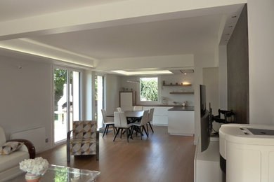 Exempel på ett modernt allrum med öppen planlösning, med vita väggar, ljust trägolv, en öppen vedspis och en väggmonterad TV