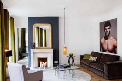 パリにある高級な中くらいなコンテンポラリースタイルのおしゃれな独立型リビング (白い壁、淡色無垢フローリング、標準型暖炉、石材の暖炉まわり、テレビなし) の写真