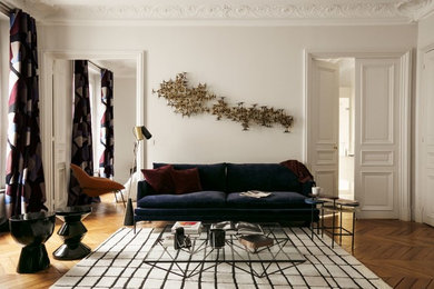 Cette image montre une salle de séjour design de taille moyenne et ouverte avec un mur gris, parquet foncé, une cheminée standard, un manteau de cheminée en pierre et un sol marron.
