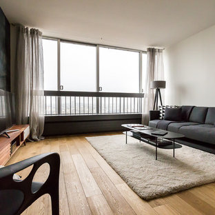 Idée de décoration pour une salle de séjour design de taille moyenne et ouverte avec un sol en bois clair, un mur noir, un téléviseur indépendant et aucune cheminée.