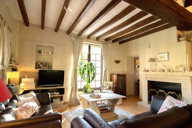Cette photo montre une salle de séjour chic de taille moyenne et fermée avec un mur beige, parquet clair, une cheminée standard, un manteau de cheminée en brique et un téléviseur indépendant.
