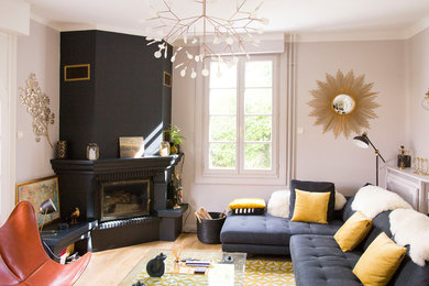 Aménagement d'une salle de séjour classique avec un mur beige, parquet clair, une cheminée d'angle, un manteau de cheminée en pierre et un sol beige.