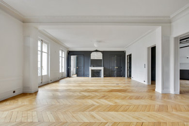 パリにあるラグジュアリーな巨大なトランジショナルスタイルのおしゃれな独立型ファミリールーム (白い壁、淡色無垢フローリング、標準型暖炉、石材の暖炉まわり、内蔵型テレビ、茶色い床) の写真