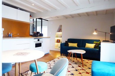 Ejemplo de sala de estar abierta costera de tamaño medio sin chimenea con paredes azules, suelo de madera clara y suelo beige