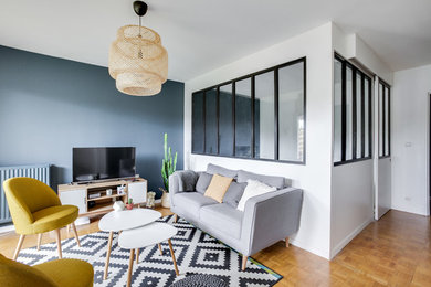 Esempio di un soggiorno scandinavo di medie dimensioni e aperto con pareti blu, parquet chiaro e TV autoportante