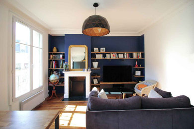 Cette photo montre une salle de séjour industrielle ouverte avec un mur bleu, parquet clair, une cheminée standard et un téléviseur indépendant.