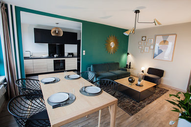 Cette image montre une grande salle de séjour design ouverte avec un mur vert, un sol en vinyl, aucune cheminée, un téléviseur indépendant et un sol beige.