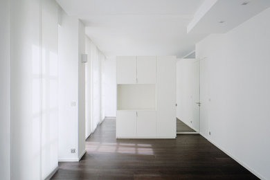 Diseño de sala de estar abierta actual con paredes blancas y suelo de madera oscura