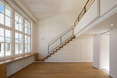 Diseño de sala de estar abierta contemporánea con paredes blancas y suelo de madera clara