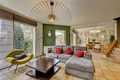 Exemple d'une grande salle de séjour tendance ouverte avec une bibliothèque ou un coin lecture, un mur vert, tomettes au sol, une cheminée standard, un manteau de cheminée en métal, un téléviseur indépendant et un sol marron.