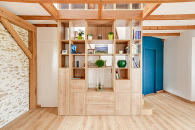 Modelo de sala de estar con biblioteca abierta campestre sin televisor con paredes blancas y suelo de madera clara