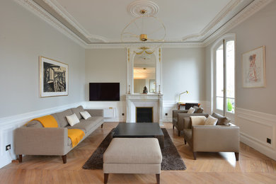 Exemple d'une salle de séjour tendance de taille moyenne et ouverte avec un mur blanc, parquet clair, une cheminée standard, un téléviseur fixé au mur et un sol marron.