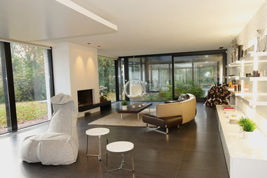 Cette photo montre une grande salle de séjour moderne ouverte avec un mur beige, un sol en carrelage de céramique, une cheminée standard, un manteau de cheminée en plâtre, un téléviseur indépendant et un sol gris.
