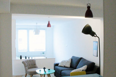 Imagen de sala de estar abierta actual pequeña con paredes blancas y suelo de madera en tonos medios