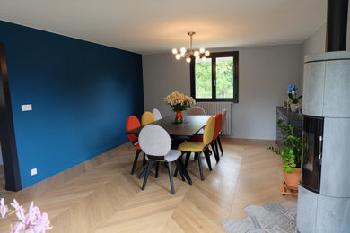Réalisation d'une grande salle à manger vintage avec un mur bleu, parquet clair, un poêle à bois et un sol beige.