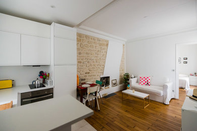 Inspiration för små minimalistiska allrum med öppen planlösning, med mellanmörkt trägolv, en öppen vedspis, vita väggar och en spiselkrans i tegelsten