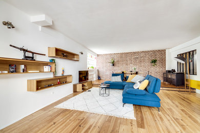 Diseño de sala de estar abierta contemporánea de tamaño medio con paredes amarillas y suelo de madera clara