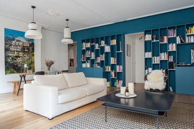 Пример оригинального дизайна: открытая гостиная комната среднего размера в современном стиле с с книжными шкафами и полками, синими стенами и светлым паркетным полом без камина, телевизора