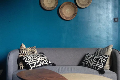 Cette image montre une petite salle de séjour nordique ouverte avec un mur bleu, un sol en bois brun et un sol marron.