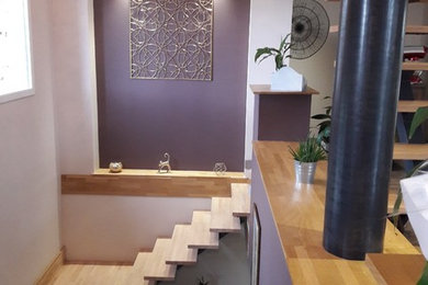 Источник вдохновения для домашнего уюта: большая открытая гостиная комната в современном стиле с коричневыми стенами, полом из ламината и фасадом камина из камня