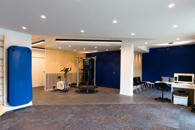 Aménagement d'une grande salle de sport contemporaine avec un mur bleu, un sol en carrelage de céramique et un sol gris.