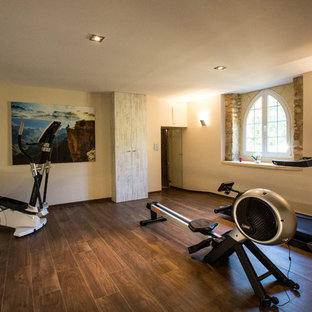 Aménagement d'une grand salle de musculation campagne avec un mur beige et un sol en bois brun.
