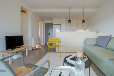 Foto de salón abierto costero pequeño con paredes blancas, suelo de baldosas de porcelana, televisor independiente y suelo marrón