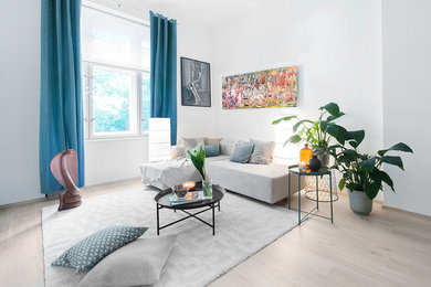 Источник вдохновения для домашнего уюта: двухуровневая гостиная комната среднего размера в современном стиле с белыми стенами, полом из ламината, телевизором на стене и серым полом