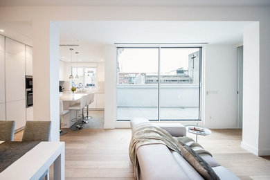 Foto de salón abierto minimalista grande con paredes blancas, suelo de madera clara y televisor colgado en la pared