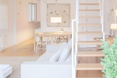 Foto de salón para visitas tipo loft escandinavo de tamaño medio sin chimenea con paredes blancas, suelo de madera en tonos medios y pared multimedia