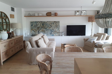 Modelo de salón abierto mediterráneo de tamaño medio con suelo laminado, televisor independiente y suelo beige