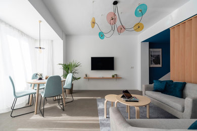 Imagen de salón abierto actual grande con paredes azules, suelo de baldosas de porcelana, televisor colgado en la pared y suelo gris