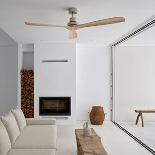Imagen de salón abierto, moderno, con paredes blancas, suelo de cemento, chimenea tradicional y suelo blanco