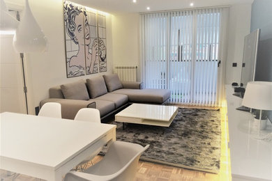 Imagen de salón abierto moderno de tamaño medio sin chimenea con paredes blancas, suelo de madera clara y televisor independiente