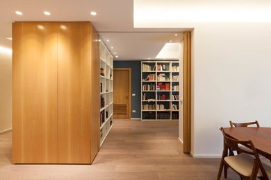 Modelo de biblioteca en casa abierta minimalista grande con suelo de madera en tonos medios