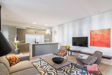 Diseño de salón abierto actual con paredes blancas, televisor colgado en la pared, suelo de madera clara y suelo beige
