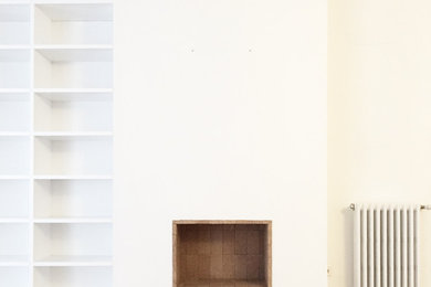 Foto de biblioteca en casa abierta escandinava de tamaño medio con paredes blancas, suelo laminado, marco de chimenea de ladrillo, televisor colgado en la pared y suelo marrón