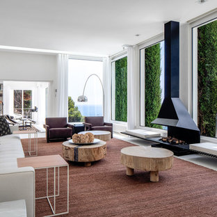 Imagen de biblioteca en casa abierta, contemporánea, grande, con paredes blancas, suelo de cemento, chimenea lineal, marco de chimenea de metal, televisor retractable y suelo blanco