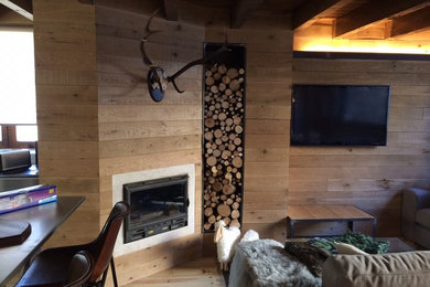 Foto de salón con barra de bar abierto escandinavo grande con paredes marrones, suelo de madera clara, chimenea de esquina, marco de chimenea de metal y televisor colgado en la pared