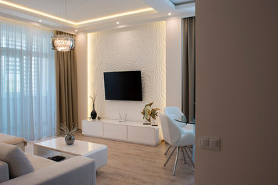 Modelo de salón abierto minimalista de tamaño medio con paredes blancas, suelo de madera clara y televisor colgado en la pared