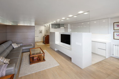 Imagen de salón para visitas abierto contemporáneo grande sin chimenea con paredes blancas, suelo de madera clara y televisor colgado en la pared