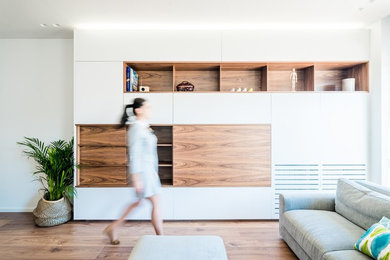 Foto de salón abierto contemporáneo con paredes blancas, suelo de madera en tonos medios, televisor colgado en la pared y suelo marrón