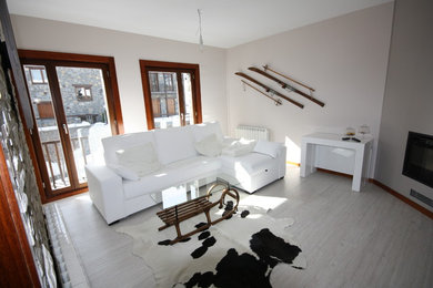 Modelo de salón para visitas cerrado actual de tamaño medio con paredes beige, suelo de madera clara y todas las chimeneas