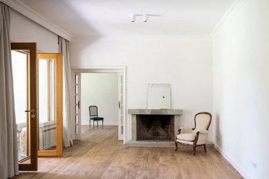 Modelo de salón abierto ecléctico grande con paredes blancas, suelo de madera en tonos medios, todas las chimeneas y marco de chimenea de piedra