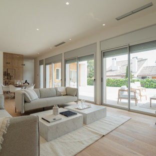 Diseño de salón abierto, contemporáneo, grande, sin televisor, con paredes blancas, suelo de madera clara y suelo beige