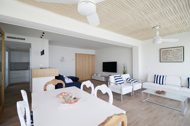 На фото: большая открытая гостиная комната в скандинавском стиле с белыми стенами, полом из керамической плитки и телевизором на стене