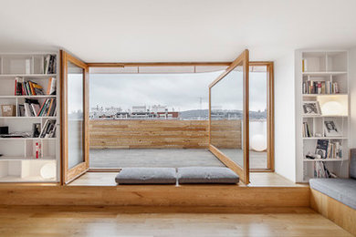 Imagen de biblioteca en casa abierta escandinava de tamaño medio sin chimenea con paredes blancas, suelo de madera en tonos medios y televisor colgado en la pared