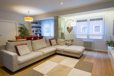 Ejemplo de salón para visitas abierto contemporáneo de tamaño medio sin chimenea con paredes blancas, suelo de madera en tonos medios y televisor colgado en la pared
